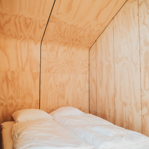 Interior minimalista de madera con cama doble en la tiny house Wikkel, Holiday park De Klepperstee, Países Bajos.