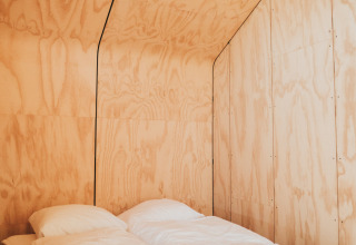 Interior minimalista de madera con cama doble en la tiny house Wikkel, Holiday park De Klepperstee, Países Bajos.