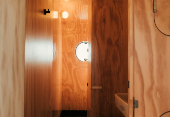 Salle de bain en bois du Wikkel tiny house, Holiday park De Klepperstee, Pays-Bas, avec fenêtre ronde.