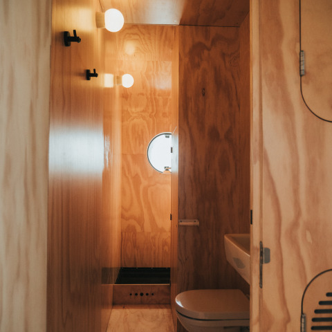 Baño de madera en la tiny house Wikkel, Holiday park De Klepperstee, Países Bajos, con ventana circular.