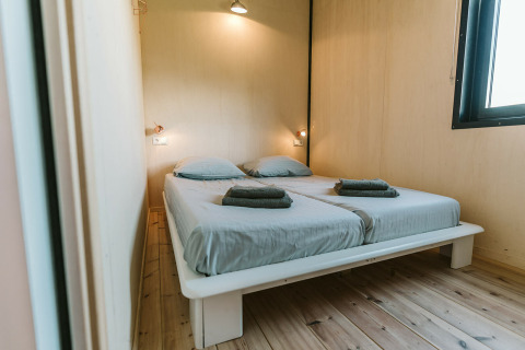Slaapkamer in The Hoagte tiny house op vakantiepark De Klepperstee in Nederland met twee eenpersoonsbedden.