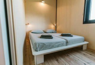 Slaapkamer in The Hoagte tiny house bij vakantiepark De Klepperstee in Nederland met twee bedden.