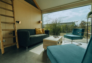 Moderne stue i lodge på Holiday park De Klepperstee i Nederlandene med store vinduer og stilfulde møbler.