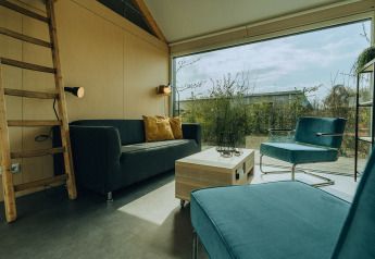 Sala moderna en una cabaña del Holiday Park De Klepperstee, Países Bajos, con amplios ventanales y muebles elegantes.