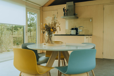 Essbereich mit bunten Stühlen und rundem Tisch in einer modernen Lodge im Holiday Park De Klepperstee, Niederlande.