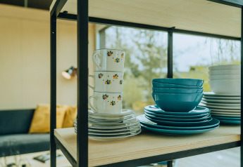 Stacked dishes and cups on a shelf in t Kroaje lodge at Holiday park De Klepperstee, Netherlands.