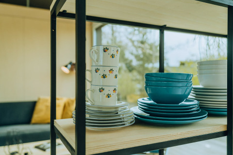 Gestapelde borden en kopjes op een plank in t Kroaje lodge bij vakantiepark De Klepperstee, Nederland.