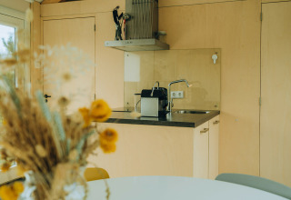 Moderne kitchenette in een lichte lodge bij t Kroaje, Holiday park De Klepperstee, Nederland, bloemen op de voorgrond.