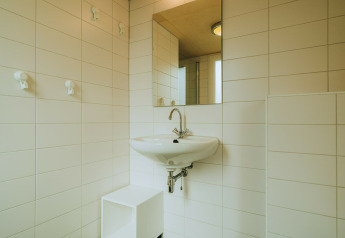 Bagno moderno piastrellato di bianco con lavandino e specchio presso De Klepperstee, Paesi Bassi.