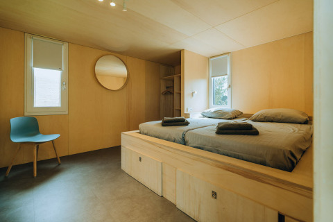 Modernes Zimmer in der Lodge 't Kroaje im Ferienpark De Klepperstee, mit Holzwänden, Doppelbett und schlichter Einrichtung.