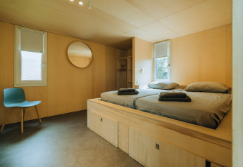 Slaapkamer in lodge 't Kroaje bij Holiday park De Klepperstee, Nederland, met minimalistisch interieur en tweepersoonsbed.