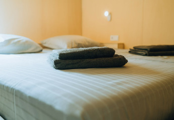 Dos juegos de toallas oscuras dobladas en una cama con sábanas a rayas en t Kroaje, De Klepperstee, Países Bajos.