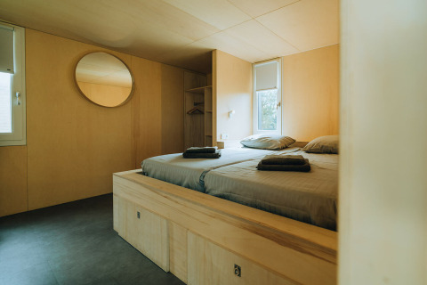 Modern bedroom at 't Kroaje lodge, Holiday Park De Klepperstee, Netherlands, with wood interior and double bed.