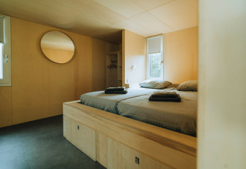 Camera moderna nel lodge 't Kroaje, Holiday Park De Klepperstee, Paesi Bassi, con interno in legno e letto matrimoniale.
