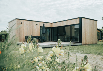 Modern natuurhuisje van hout op Vakantiepark De Klepperstee in Nederland, omringd door bloemen.