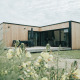 Modern wooden nature house at Holiday park De Klepperstee in the Netherlands, surrounded by flowers.