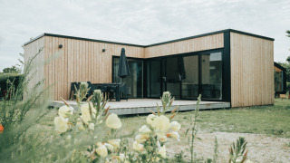 Casa de naturaleza moderna en madera en Holiday park De Klepperstee, Países Bajos, rodeada de flores.
