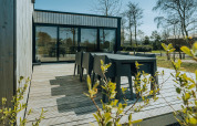 Terrazza esterna con tavolo nero al Huus van Hanse, parco vacanze De Klepperstee, Paesi Bassi.