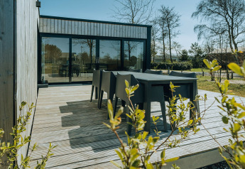 Terrazza esterna con tavolo nero al Huus van Hanse, parco vacanze De Klepperstee, Paesi Bassi.