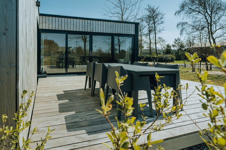Outdoor terrace with black dining set at Huus van Hanse, Nature House, Holiday Park De Klepperstee, Netherlands.