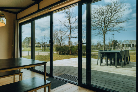 Vue depuis Huus van Hanse à De Klepperstee, avec portes vitrées et terrasse et espace vert extérieur.