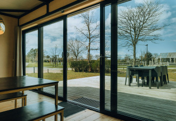 Uitzicht vanuit Huus van Hanse op vakantiepark De Klepperstee met glazen schuifdeuren en terras.