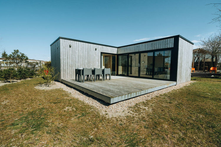 Modern wooden cabin at Huus van Hanse, De Klepperstee, Netherlands, with spacious deck and dining area.