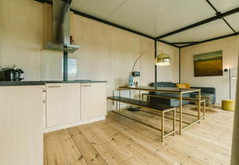 Moderne woonkamer en keuken met houten vloer in Huus van Hanse, een natuurhuis in De Klepperstee, Nederland.