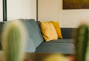 Modern grey sofa with yellow cushions at Huus van Hanse, Nature house, Holiday park De Klepperstee, Netherlands.