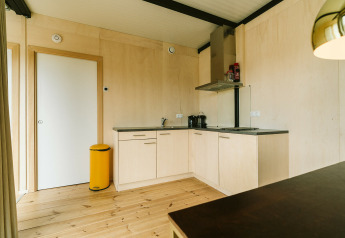 Coin cuisine moderne en bois clair avec poubelle jaune, Huus van Hanse, Holiday park De Klepperstee, Pays-Bas.