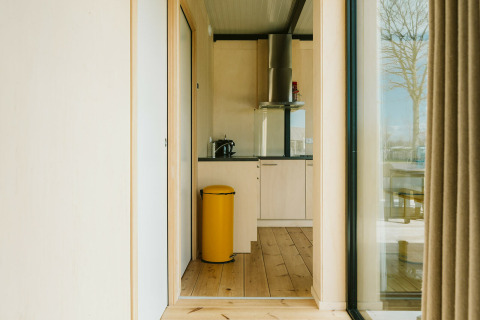 Lichte, moderne keuken met gele vuilbak en houten vloer in het Nature house bij De Klepperstee, Nederland.
