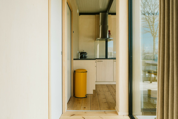 Bright modern kitchen with yellow trash bin and wood accents at Nature house, De Klepperstee, the Netherlands.