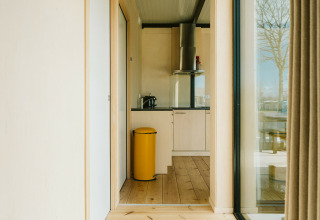 Heldere, moderne keuken met gele prullenbak en houten vloer in Nature house bij De Klepperstee, Nederland.
