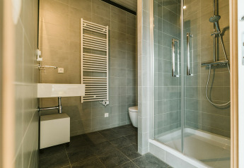 Baño moderno con ducha, inodoro, lavabo y radiador para toallas en Huus van Hanse, De Klepperstee.