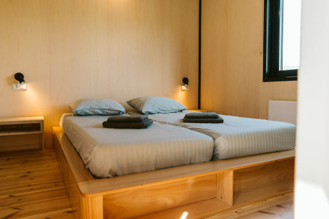 Dormitorio moderno con cama doble, interior de madera y ventana grande en Huus van Hanse, De Klepperstee, Países Bajos.