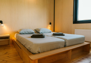Moderne slaapkamer met twee eenpersoonsbedden en houten decor in het Nature house op Holiday park De Klepperstee.
