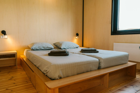 Moderne slaapkamer met twee eenpersoonsbedden en houten decor in het Nature house op Holiday park De Klepperstee.