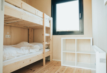 Lichte kamer met houten stapelbed, raam en witte kast in Nature house op De Klepperstee, Nederland.