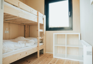 Lichte kamer met houten stapelbed, raam en witte kast in Nature house op De Klepperstee, Nederland.