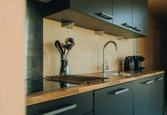 Cucina moderna con piano in legno, mobili grigi e macchina da caffè al Duunroos lodge nei Paesi Bassi.