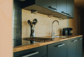 Cocina moderna con encimera de madera, armarios grises y cafetera en Duunroos, parque De Klepperstee, Países Bajos.