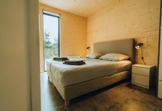 Dormitorio moderno con cama doble en Duunroos, lodge del Holiday park De Klepperstee en Países Bajos.