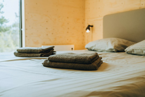 Sfeervolle slaapkamer in Duunroos, vakantiepark De Klepperstee, Nederland met nette handdoeken op bed.