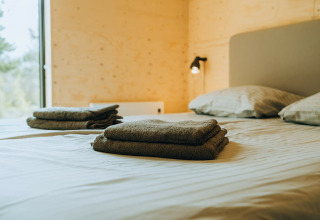 Sfeervolle slaapkamer in Duunroos, vakantiepark De Klepperstee, Nederland met nette handdoeken op bed.