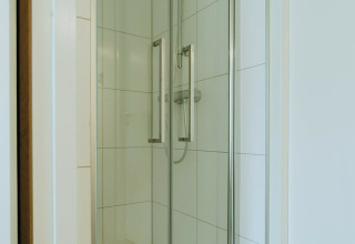 Modern shower cabin with glass doors at Duunroos, a lodge in Holiday park De Klepperstee, Netherlands.