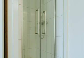 Moderne douchecabine met glazen deuren bij Duunroos, een lodge in vakantiepark De Klepperstee, Nederland.