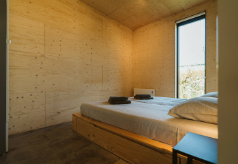 Moderne slaapkamer in een lodge op De Klepperstee, Nederland, met houten muren en grote ramen.