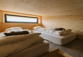 Twee eenvoudige bedden met wit linnen in een houten kamer bij Lodge Kleproos, De Klepperstee, Nederland.