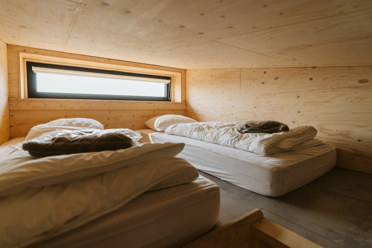 Two simple beds with white bedding in a wood-paneled room at Lodge Kleproos, De Klepperstee, Netherlands.