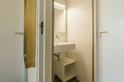 Baño moderno con lavabo blanco, espejo y estante en Kleproos, Holiday park De Klepperstee, Países Bajos.